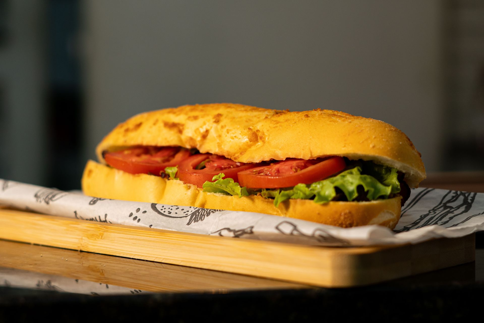 Delicious sub sandwich with fresh tomatoes and lettuce on a wooden board.